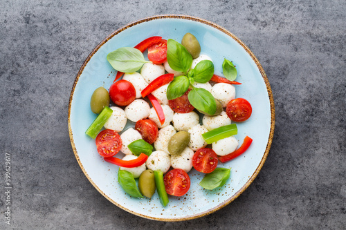 Delicious caprese salad with ripe cherry tomatoes and mini mozzarella cheese balls with fresh basil leaves.