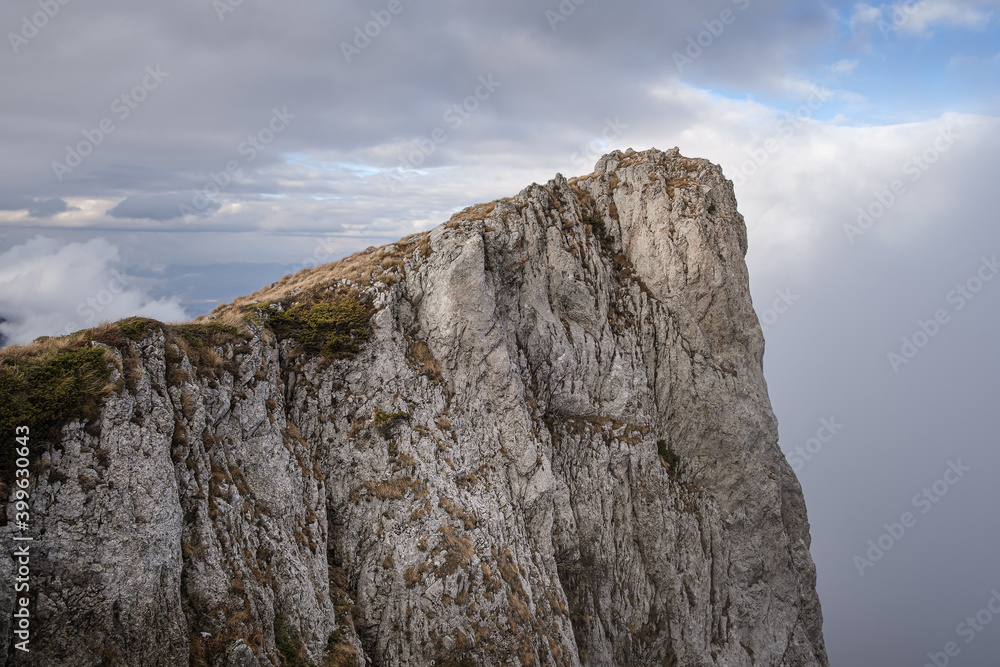 Rocky, steep, vertical cliff on Dry mountain (Suva planina) covered with dry, orange grass at autumn and cloudy blue sky Rocky, steep, vertical cliff on Dry mountain (Suva planina) covered with dry, orange grass at autumn and cloudy blue sky