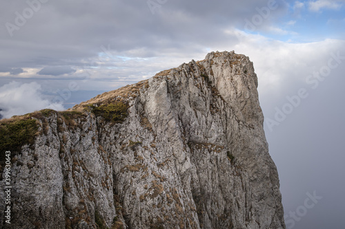 Rocky, steep, vertical cliff on Dry mountain (Suva planina) covered with dry, orange grass at autumn and cloudy blue sky