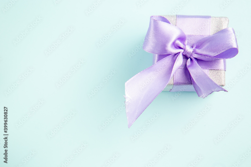 top view cute little present tied with bow on a blue background gift photo xmas new year color top view cute little present tied with bow on a blue background gift photo xmas new year color
