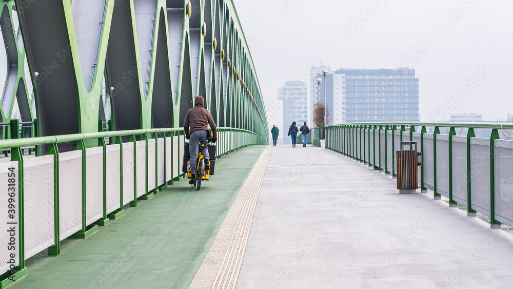 Courier on bicycle on the new bridge in Bratislava distributes food