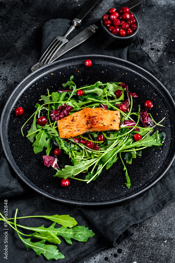Seafood salad with trout, arugula, lettuce and cranberries. Black background. Top view
