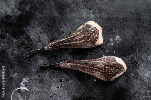 Raw monkfish without a head. Black background. Top view