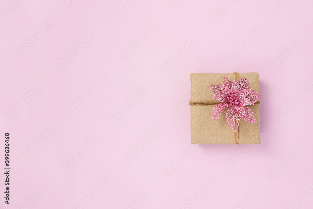 Present box made of kraft paper decorated with decorative poinsettia on pink background. DIY gift concept. Copy space Present box made of kraft paper decorated with decorative poinsettia on pink background. DIY gift concept. Copy space