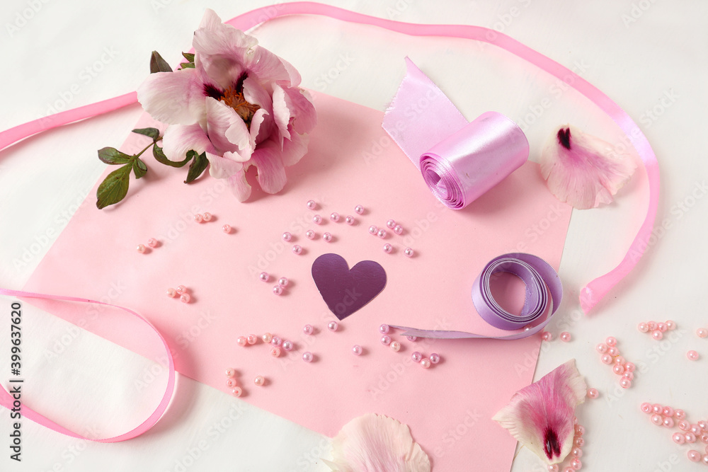 Heart among beads and ribbons with a peony flower on a pink background, top view-the concept of fun from needlework Heart among beads and ribbons with a peony flower on a pink background, top view-the concept of fun from needlework