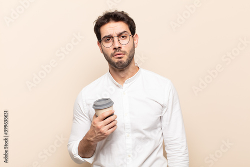 young handsome man feeling sad and whiney with an unhappy look, crying with a negative and frustrated attitude photo