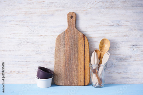 Wooden cutting board and kitchen utensils on wooden background photo