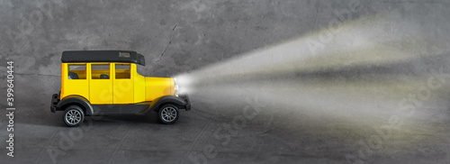 Yellow toy retro car on gray background. Trendy colors 2021.