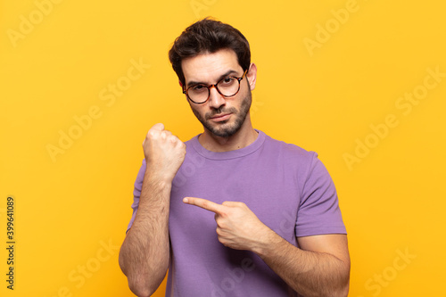 young handsome man looking impatient and angry, pointing at watch, asking for punctuality, wants to be on time photo