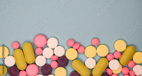 A top view of a heap of colourful medicine pills and on blue background. Medical concept.