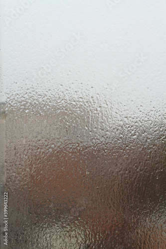 Street view through an ice-covered window outside. Dull cloudy winter day.