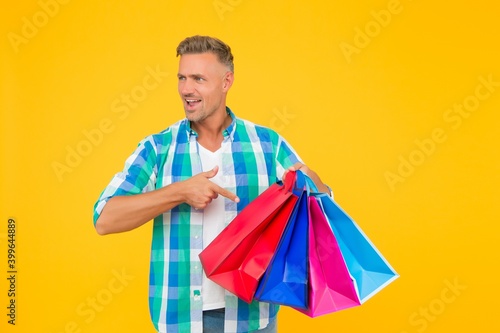 successful mature shopper man pointing finger on shopping bags, clearance sale