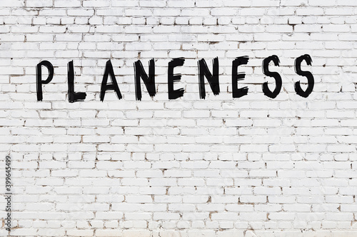 Foto White wall with black paint inscription planeness on it