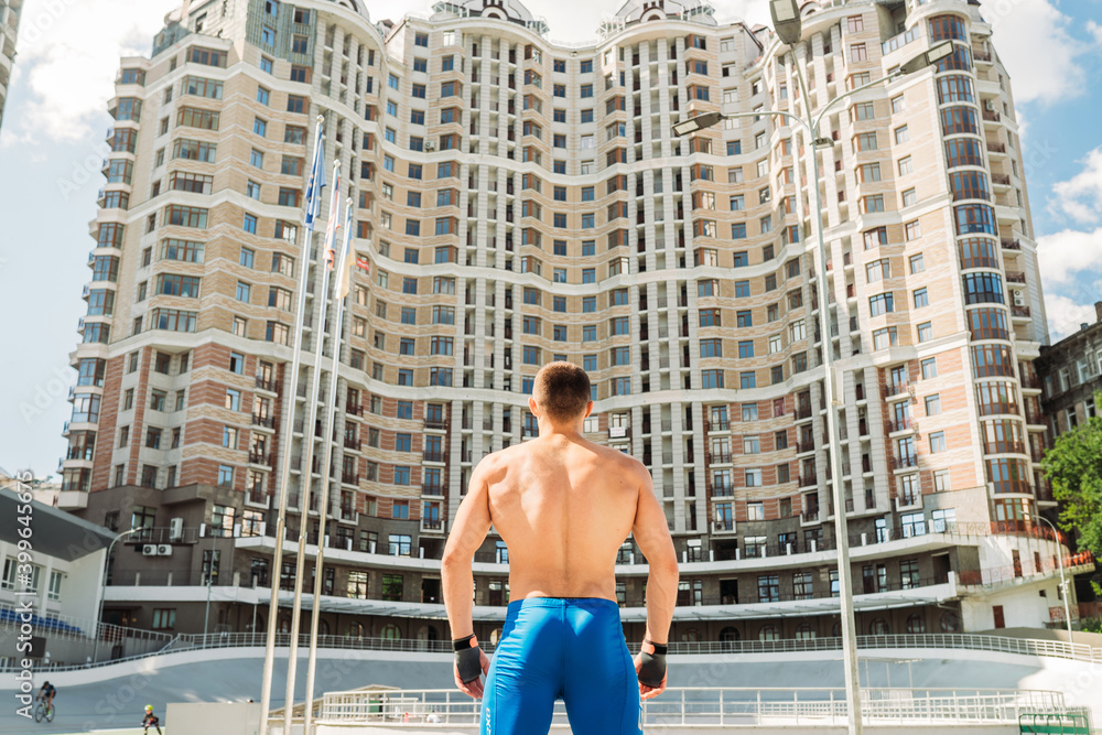 Muscular guy with a naked torso on the background of a tall building