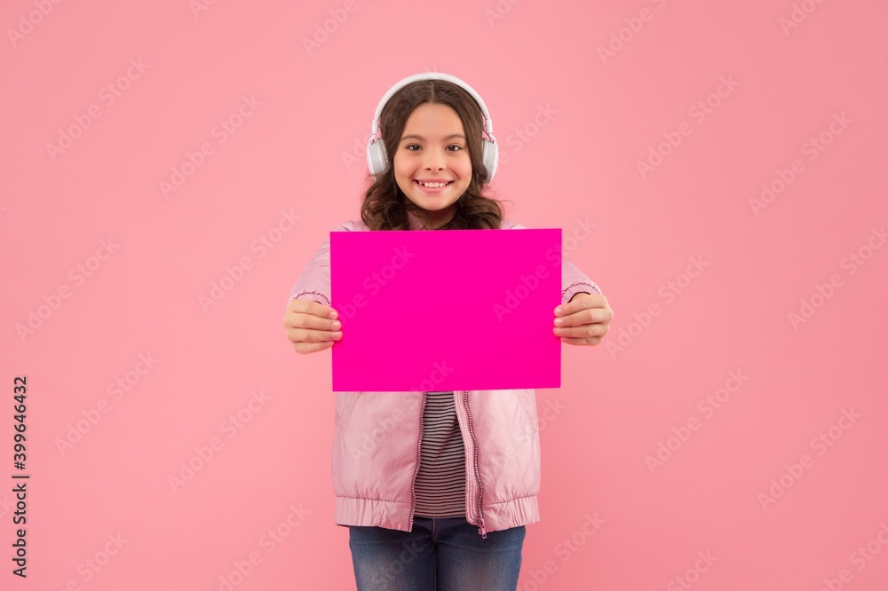 cheerful kid wearing earphones and showing empty paper for copy space, announcement cheerful kid wearing earphones and showing empty paper for copy space, announcement
