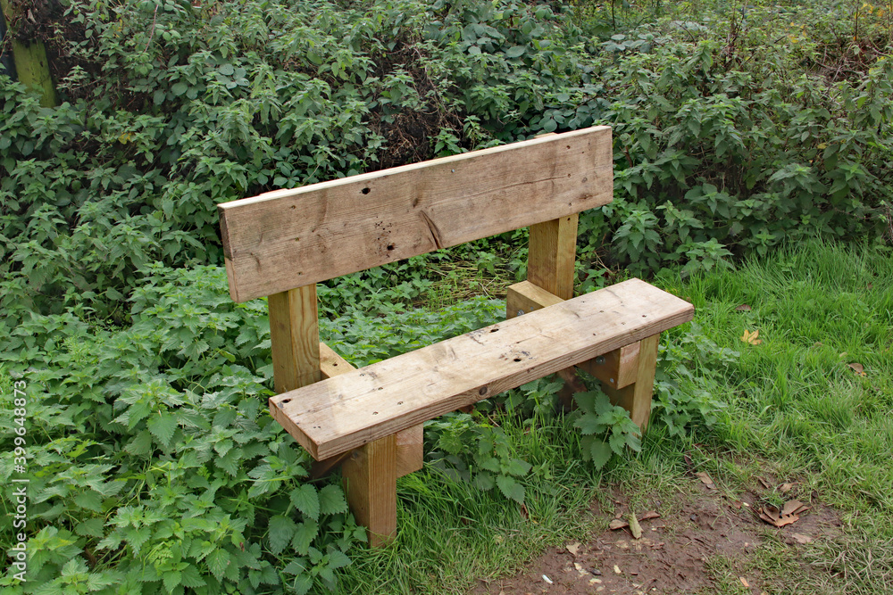 A basic timber bench set beside the canal towpath, for weary walkers to take a rest