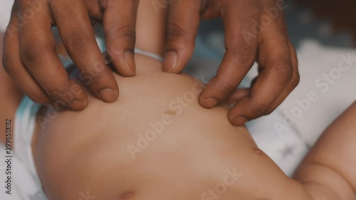Vlose up black father tickling tummy of his newborn baby . Fatherhood and multiracial family. High quality 4k footage photo