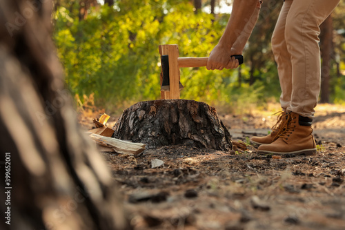 Man chopping firewood with axe in forest, closeup