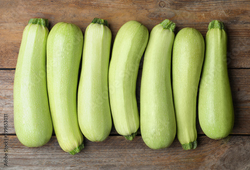 Raw green zucchinis on wooden table, flat lay