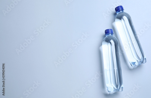 Plastic bottles with water on white background, flat lay. Space for text