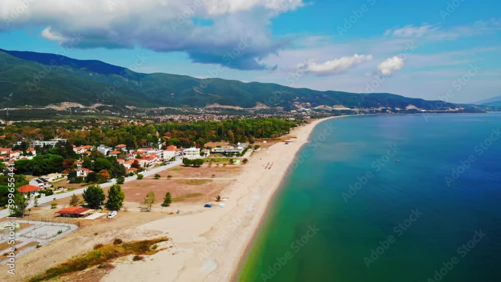 Panorama of the Asprovalta with multiple buildings and greenery, green hills on the background. Aegean sea coast. Long beach along the town. Sunny day. Greece Panorama of the Asprovalta with multiple buildings and greenery, green hills on the background. Aegean sea coast. Long beach along the town. Sunny day. Greece