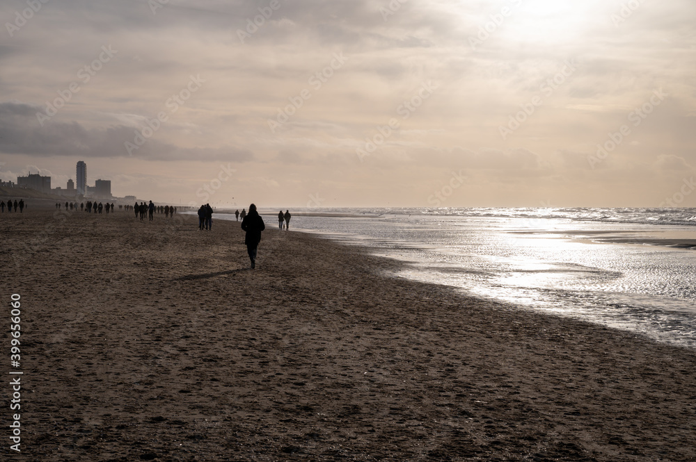 Winter walking on wide sandy beach of North sea near Zandvoort in Netherlands Winter walking on wide sandy beach of North sea near Zandvoort in Netherlands