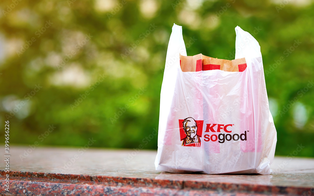 Minsk, Belarus. May 2020. Plastic bag with KFC combo set against nature  background, takeout from restaurant. Take away food from KFC restaurants  chain. Kentucky Fried Chicken fast food chain Stock Photo