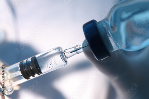 Doctor filling syringe with vaccine from vial, closeup