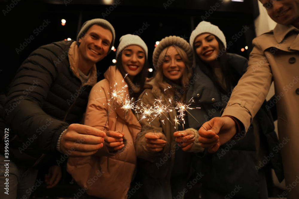 Group of people holding burning sparklers, focus on hands