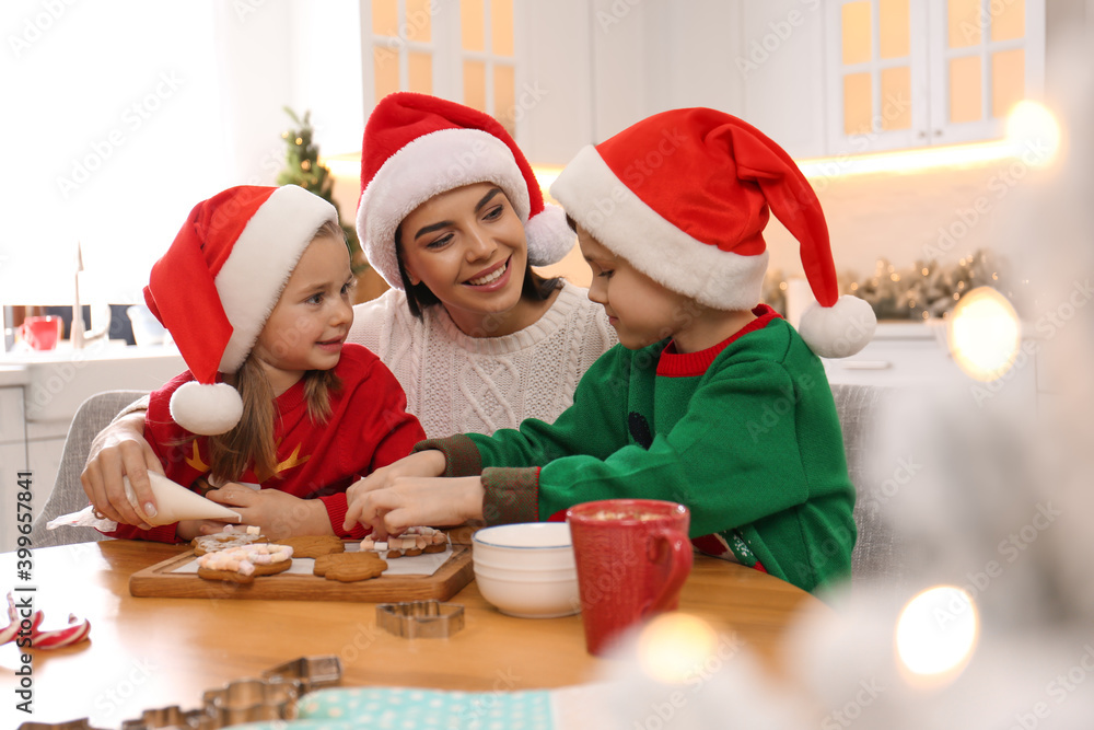 Mother and her cute little children decorating tasty Christmas cookies at table in kitchen Mother and her cute little children decorating tasty Christmas cookies at table in kitchen