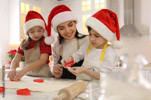 Mother and her cute little children making Christmas cookies in kitchen