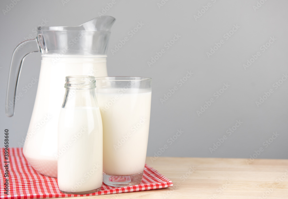 A jug and bottle of milk glass on a wooden table on background..Raw milk is high in calcium and protein to drink for all ages..Milk consumption nutritious and healthy dairy products concept.. A jug and bottle of milk glass on a wooden table on background..Raw milk is high in calcium and protein to drink for all ages..Milk consumption nutritious and healthy dairy products concept..