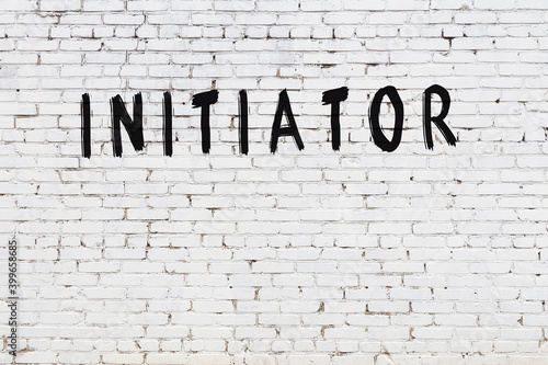 White wall with black paint inscription initiator on it