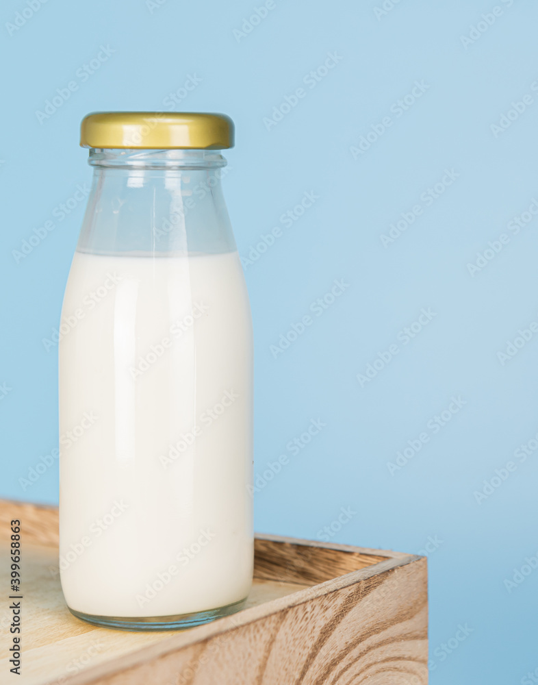 Bottles with fresh milk on a wooden table on a blue background..Raw milk is high in calcium and protein to drink for all ages..Milk consumption nutritious and healthy dairy products concept. Bottles with fresh milk on a wooden table on a blue background..Raw milk is high in calcium and protein to drink for all ages..Milk consumption nutritious and healthy dairy products concept.