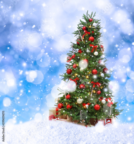 Beautiful decorated Christmas tree and snow on blue background. Bokeh effect