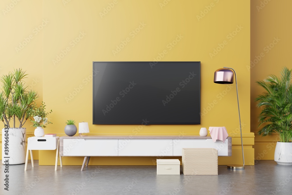 TV wall console in modern living room with lamp,table,flower and plant on yellow illuminating wall background.