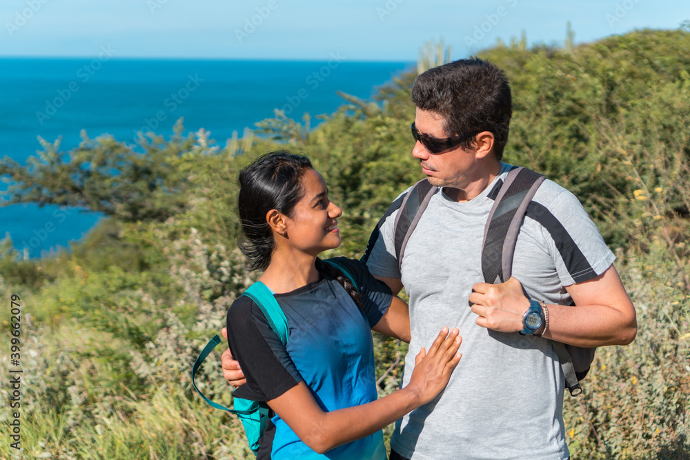 A young couple takes a walk in the mountains. Man and woman standing on the top of the mountain looking at each other A young couple takes a walk in the mountains. Man and woman standing on the top of the mountain looking at each other