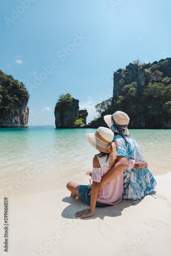 Asian mother and child girl sitting on the beach and enjoying with beautiful nature together in their vacation. Summer holidays and family travel concept. Travelling in Thailand.