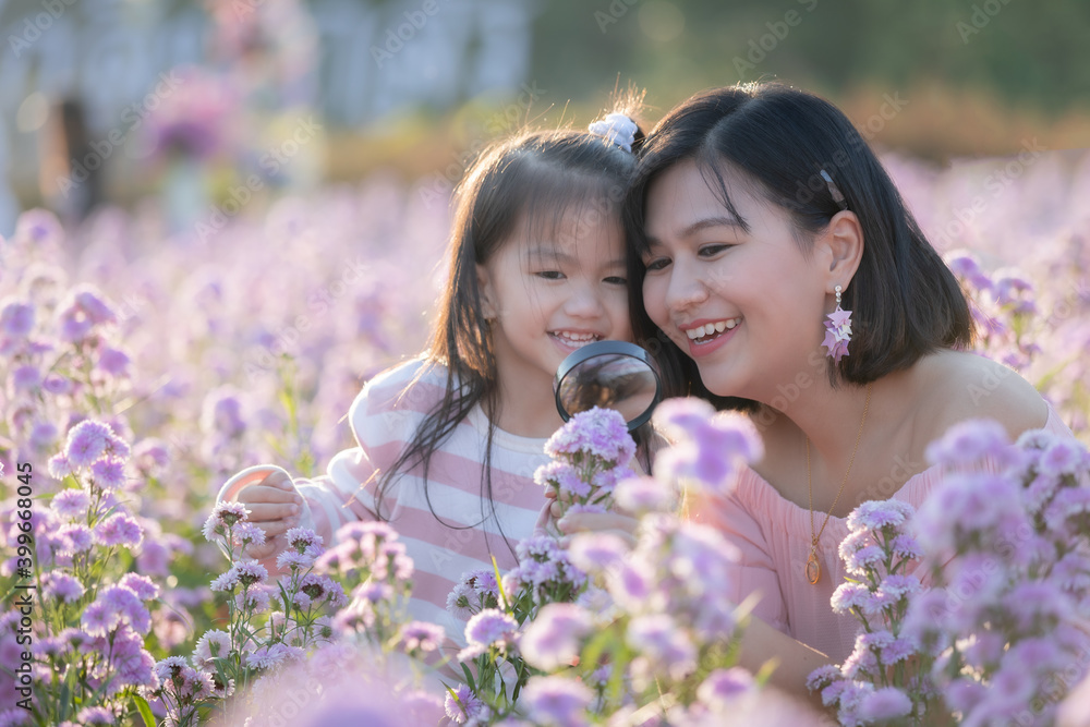 Cute asian child girl and her mother enjoying with beautiful flower together and little girl holding magnifier looking on flower with fun and curiously in the flower garden. Cute asian child girl and her mother enjoying with beautiful flower together and little girl holding magnifier looking on flower with fun and curiously in the flower garden.