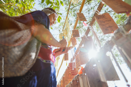 Asian traveller woman writing wishes on wooden plates to hang with sunlight while she travel on her vacation.
