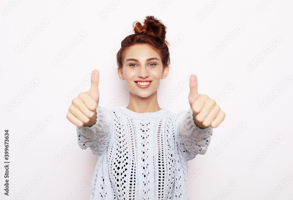 Happy young caucasian female making thumb up sign and smiling cheerfully, showing her support and respect to someone. Happy young caucasian female making thumb up sign and smiling cheerfully, showing her support and respect to someone.