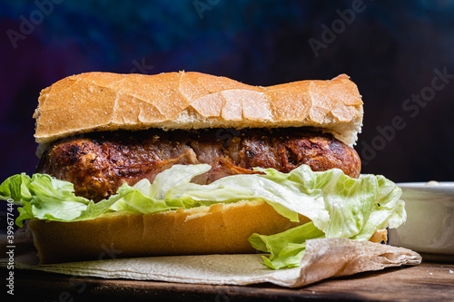 primer plano de choripan comida tipica y tradicional de argentina sandwich de pan con chorizo de cerdo con condimentos salsa criolla lechuga cebolla pimiento morron tomate mayonesa kechup y moztaza photo