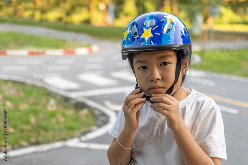 Asian girl learns to ride bike in park. Portrait of a cute kid on bicycle. © Noey smiley