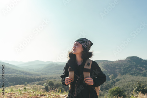 Adventure traveller female happy smile with backpack, Asian woman climber happy looking beautiful view on the mountain. Tourist backpacker hike standing top mountain with sunrise on the morning.