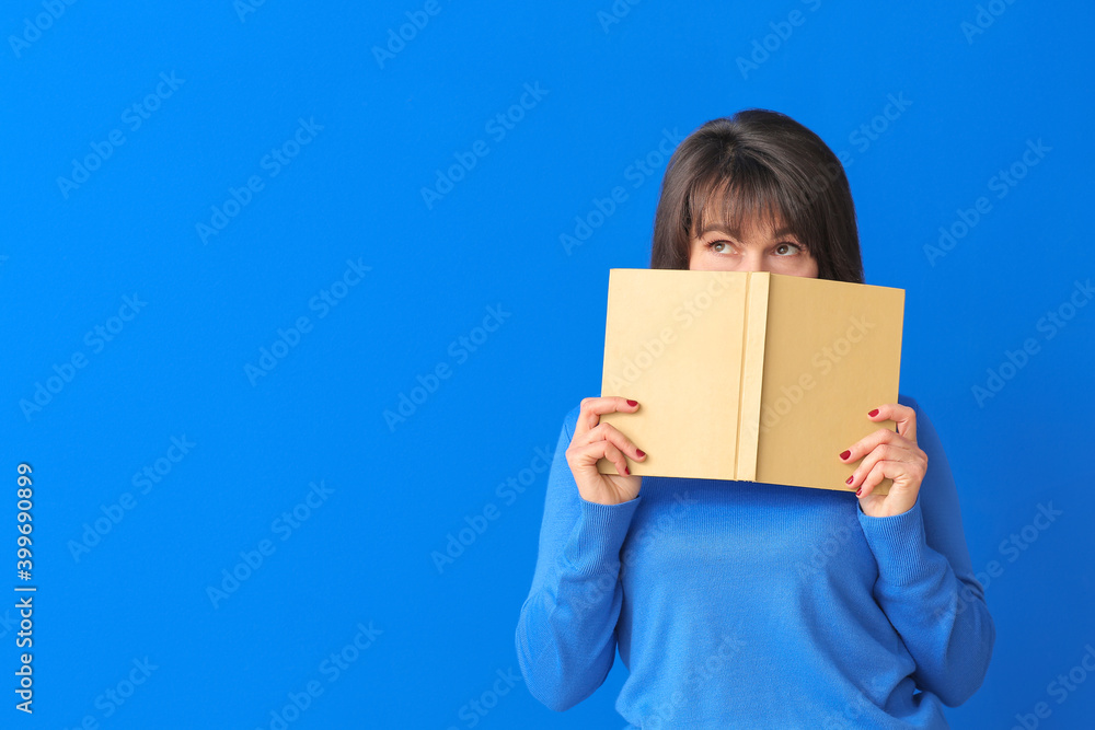 Beautiful mature woman reading book on color background Beautiful mature woman reading book on color background