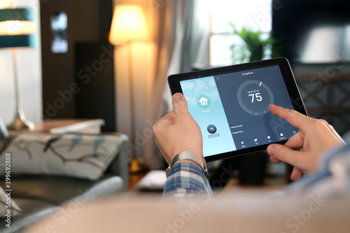 Man is Adjusting a temperature using a tablet with smart home app in modern living room photo