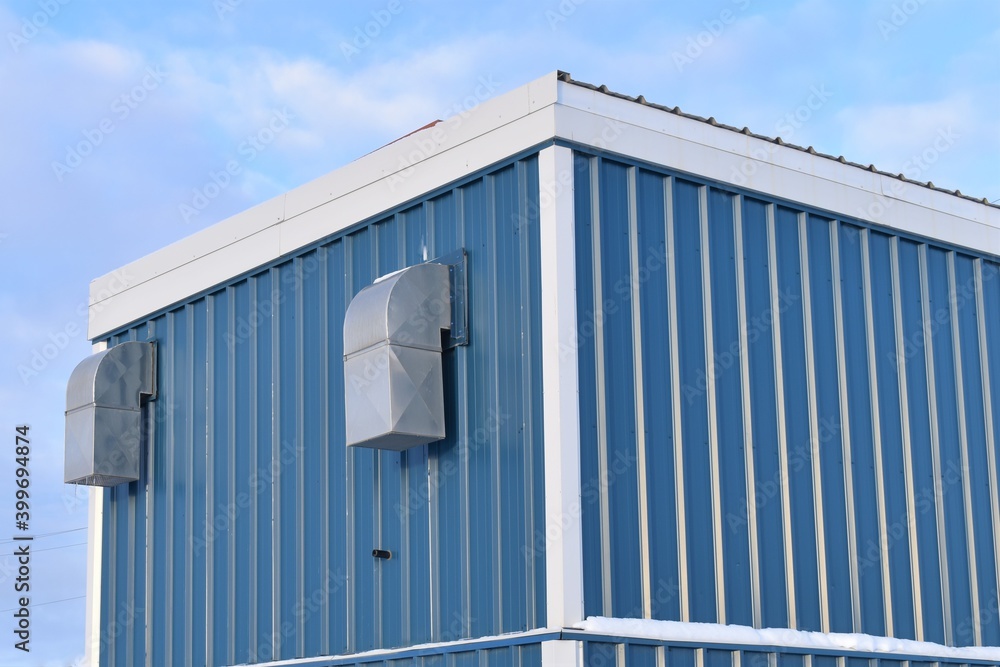 Blue, silver and white building with silver ductwork against blue sky. Interesting abstract shapes. Blue, silver and white building with silver ductwork against blue sky. Interesting abstract shapes.