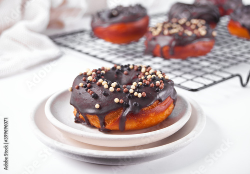 Doughnut on the baking rack and on the plate glazed with chocolate cream or icing. Breakfast concept.
