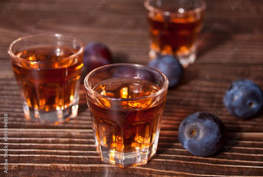 Plum vodka or brandy with fresh plums on the wooden table. Plum vodka or brandy with fresh plums on the wooden table.