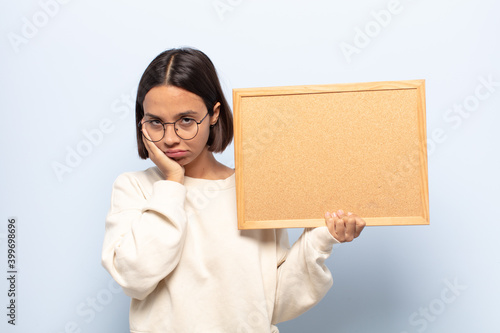 young latin woman feeling bored, frustrated and sleepy after a tiresome, dull and tedious task, holding face with hand